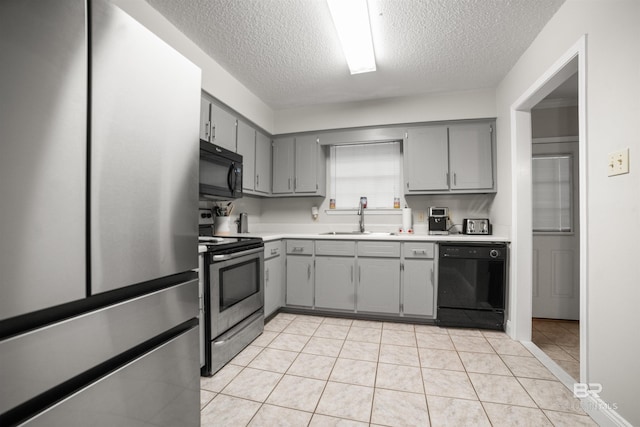 kitchen with gray cabinetry, sink, light tile patterned floors, and black appliances