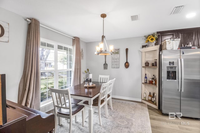 dining room with light hardwood / wood-style flooring, a wealth of natural light, and an inviting chandelier