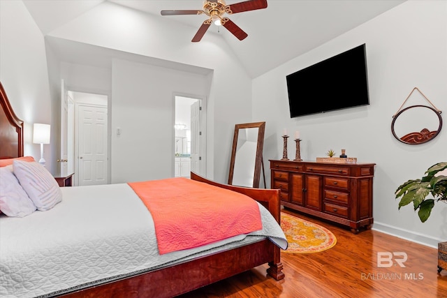 bedroom with connected bathroom, baseboards, lofted ceiling, wood finished floors, and a ceiling fan