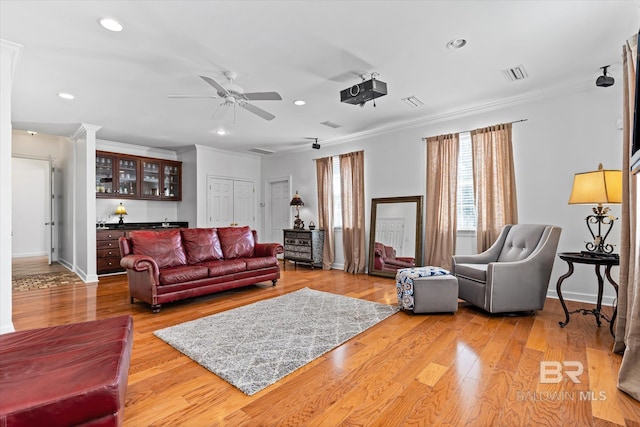 living room featuring visible vents, crown molding, bar, wood finished floors, and a ceiling fan