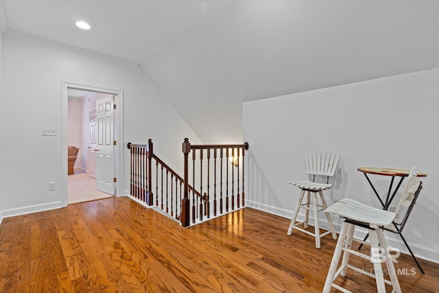 interior space with wood finished floors, an upstairs landing, baseboards, and lofted ceiling