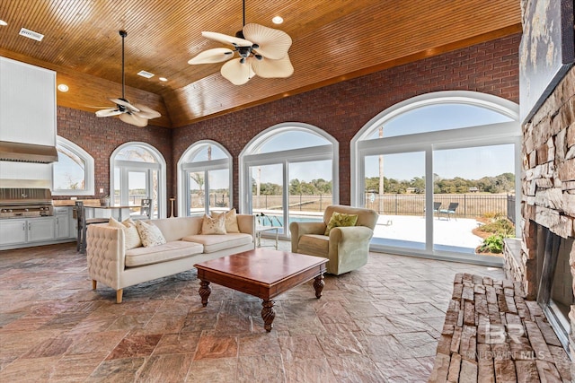 living room featuring visible vents, brick wall, high vaulted ceiling, ceiling fan, and wood ceiling