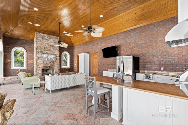 view of patio featuring outdoor wet bar, exterior kitchen, an outdoor living space with a fireplace, and a ceiling fan