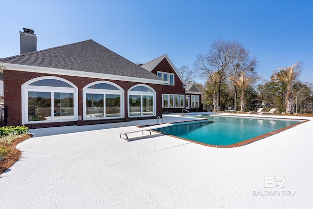 pool with a diving board and a patio area