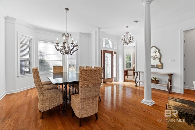 dining room featuring ornate columns, visible vents, an inviting chandelier, and wood finished floors