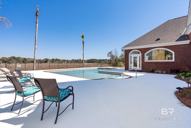 community pool with a patio and fence