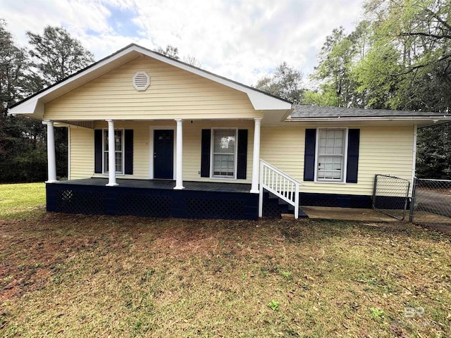 view of front of home with a porch, a gate, fence, and a front lawn