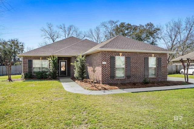 single story home featuring a front yard, fence, brick siding, and a shingled roof