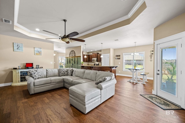 living area featuring dark wood finished floors, visible vents, crown molding, and a tray ceiling