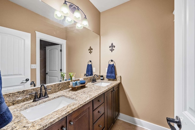 full bath with a sink, baseboards, double vanity, and tile patterned flooring