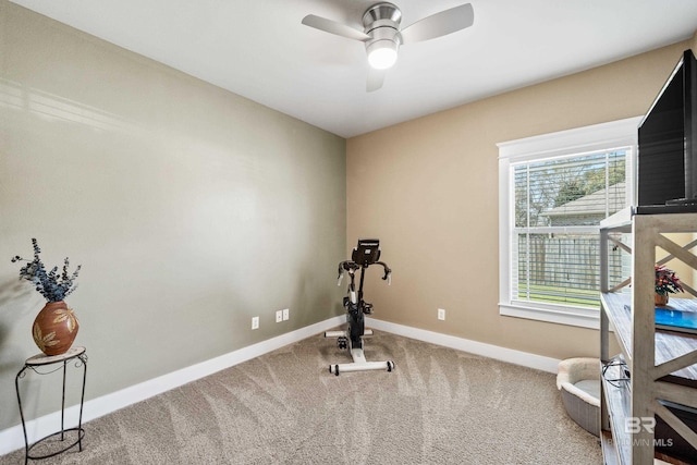 exercise room with a ceiling fan, baseboards, and carpet floors