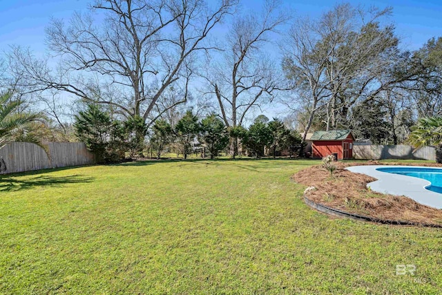 view of yard with a fenced in pool, a storage unit, a fenced backyard, and an outdoor structure