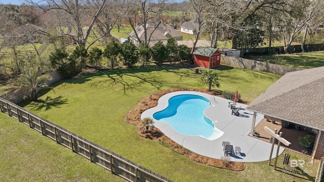 view of pool with an outbuilding, a lawn, a patio, a fenced backyard, and a storage shed