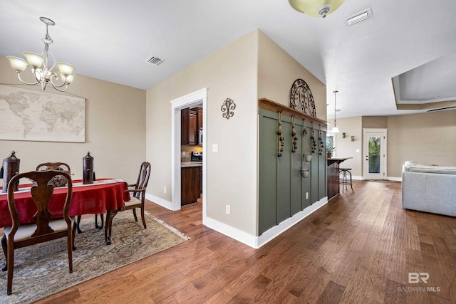 dining space with visible vents, baseboards, an inviting chandelier, and wood finished floors