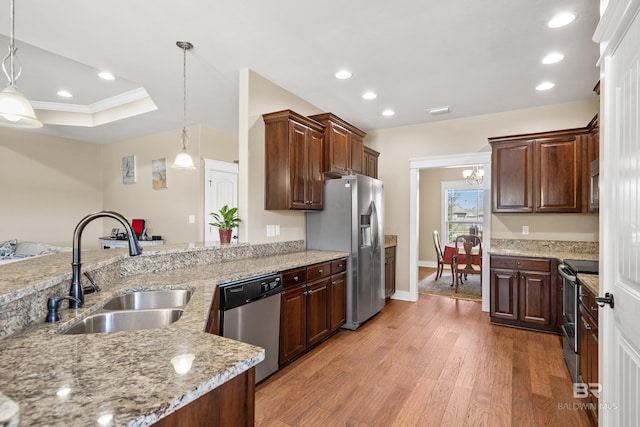 kitchen with light stone countertops, a tray ceiling, a sink, appliances with stainless steel finishes, and light wood-type flooring