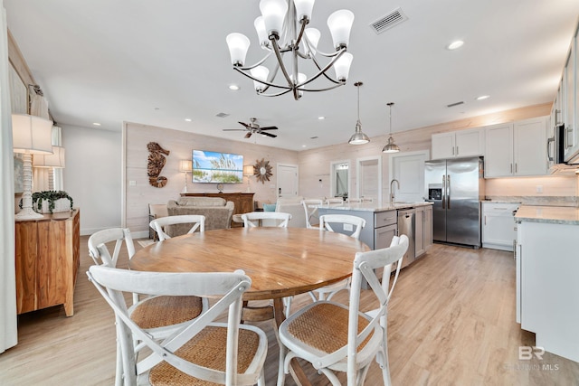 dining room featuring light hardwood / wood-style floors, sink, and ceiling fan with notable chandelier