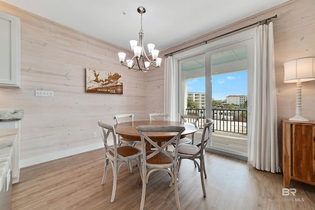 dining space featuring wooden walls, light wood-type flooring, and an inviting chandelier