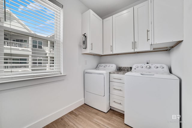 clothes washing area with washer and dryer, cabinets, and light wood-type flooring