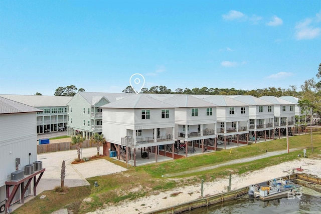 rear view of house with a water view, a lawn, and a patio area