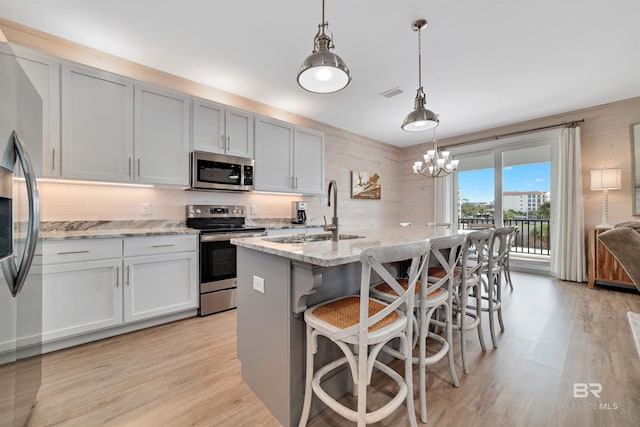 kitchen featuring light hardwood / wood-style floors, stainless steel appliances, a notable chandelier, pendant lighting, and sink