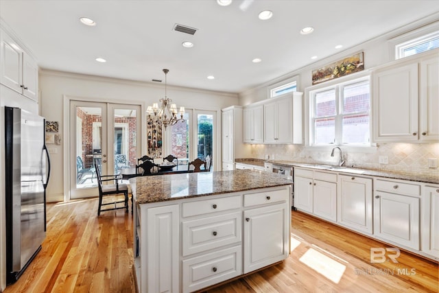 kitchen with stainless steel appliances, a kitchen island, a sink, french doors, and crown molding