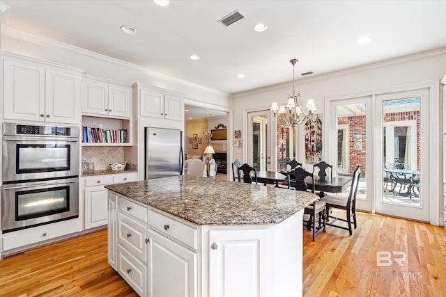 kitchen featuring stainless steel appliances, a center island, light wood-type flooring, and visible vents