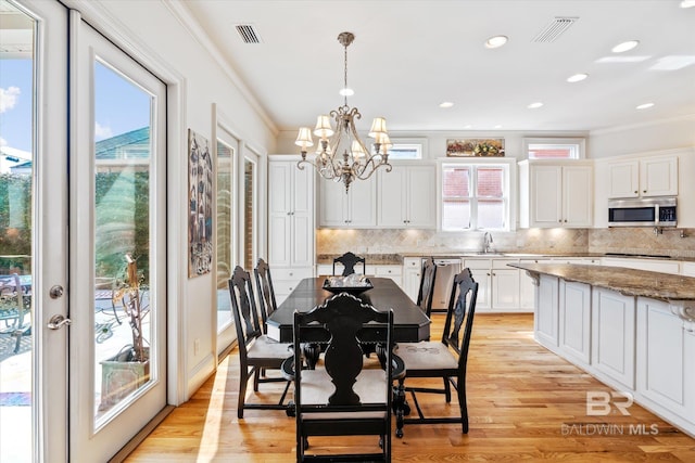 dining space featuring light wood finished floors, visible vents, a chandelier, and ornamental molding