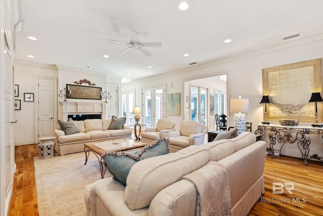 living room with a fireplace, recessed lighting, visible vents, ornamental molding, and wood finished floors