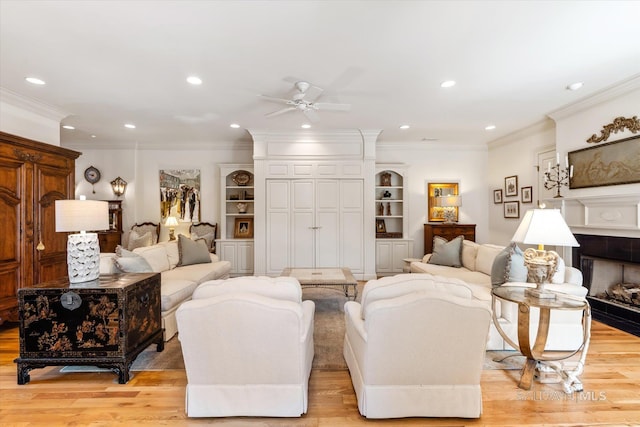 living room with light wood-type flooring, a fireplace, ornamental molding, and recessed lighting