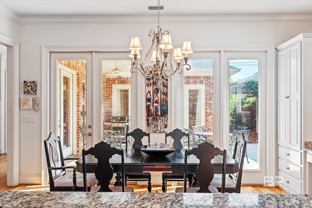 dining area featuring light wood-style flooring, a notable chandelier, visible vents, french doors, and ornamental molding