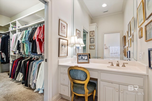 bathroom with ornamental molding, a walk in closet, visible vents, and vanity