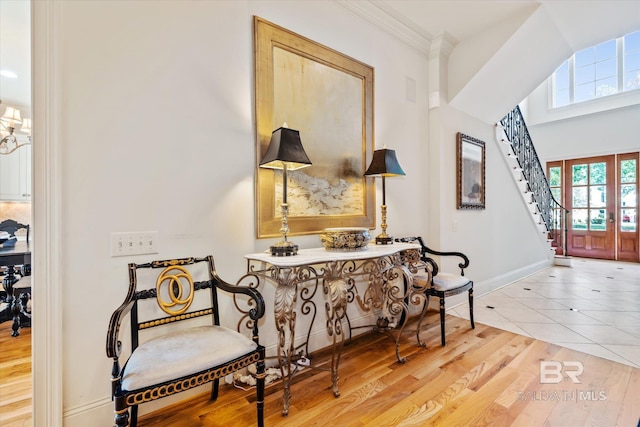 living area with french doors, crown molding, stairway, light wood-type flooring, and baseboards