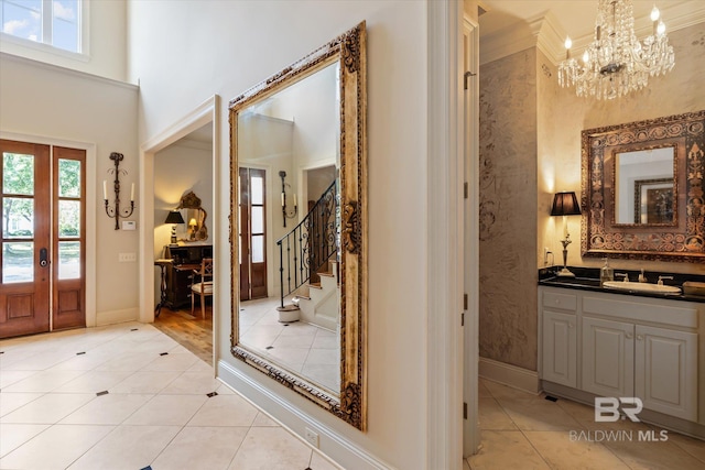 entrance foyer featuring light tile patterned flooring, a notable chandelier, a high ceiling, baseboards, and stairway