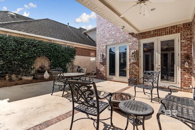 view of patio with outdoor dining space, french doors, a fireplace, and ceiling fan