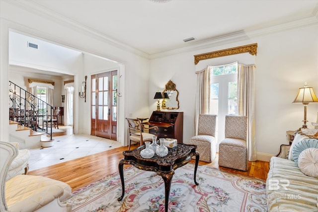 living area featuring wood finished floors, visible vents, crown molding, and stairs