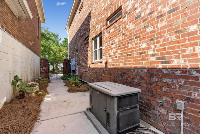 view of side of home featuring a gate and brick siding