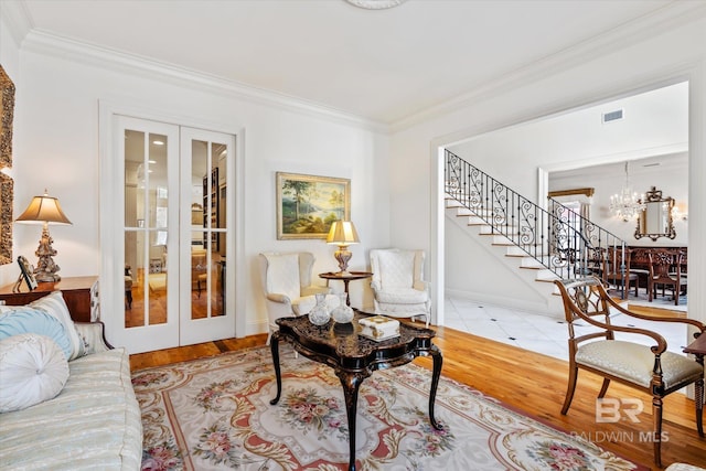 living area with a chandelier, french doors, and ornamental molding