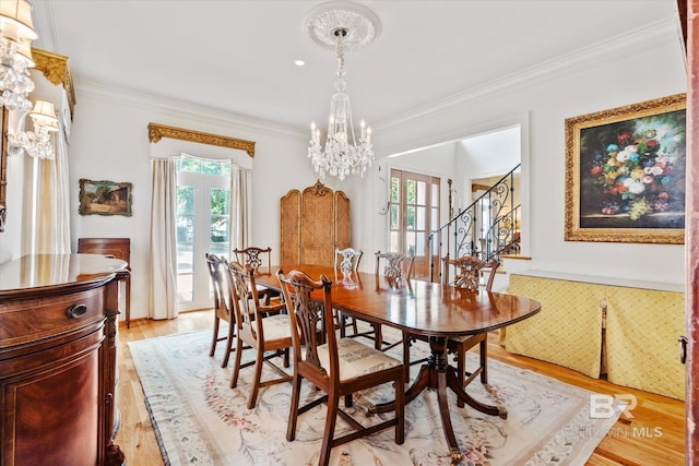 dining area with a notable chandelier, light wood-style floors, stairway, a wealth of natural light, and crown molding