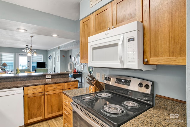 kitchen with light wood-type flooring, white appliances, and dark stone countertops