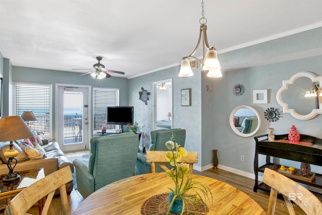 dining space featuring light hardwood / wood-style floors, ornamental molding, and ceiling fan with notable chandelier