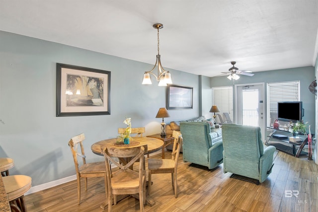 dining area with hardwood / wood-style floors and ceiling fan with notable chandelier