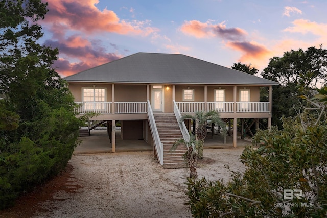 back house at dusk featuring a porch