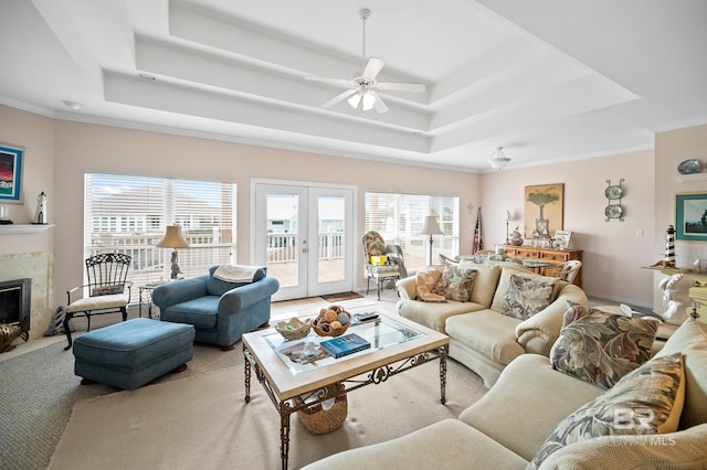 carpeted living room with french doors, a high end fireplace, ceiling fan, and a raised ceiling