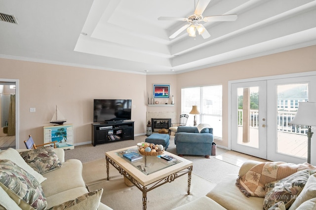 living room featuring french doors, crown molding, light tile patterned floors, a tray ceiling, and ceiling fan