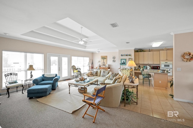 tiled living room featuring french doors, ceiling fan, and a raised ceiling