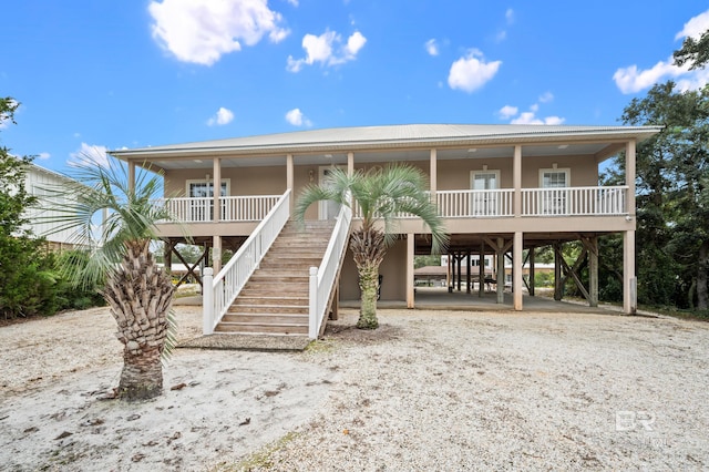 raised beach house featuring covered porch and a carport