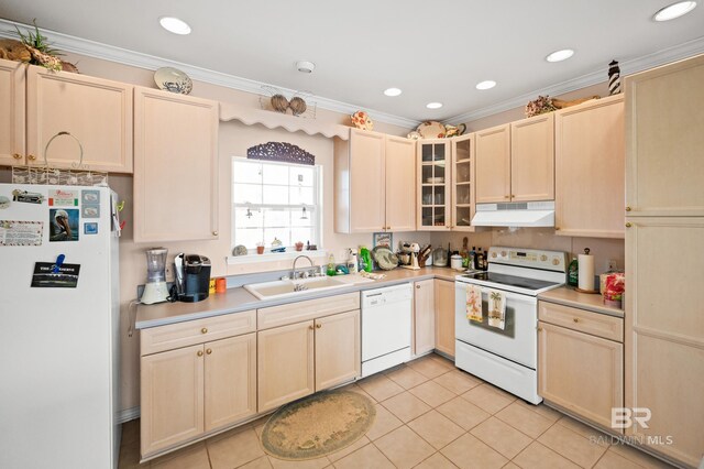 kitchen with crown molding, light tile patterned floors, white appliances, and sink