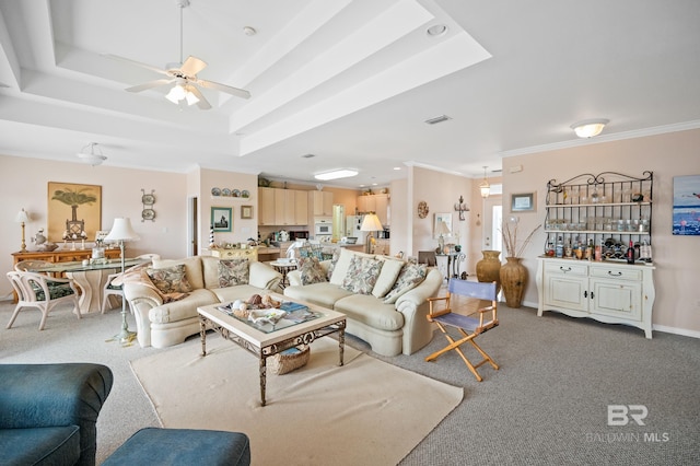 carpeted living room with ceiling fan, crown molding, and a tray ceiling