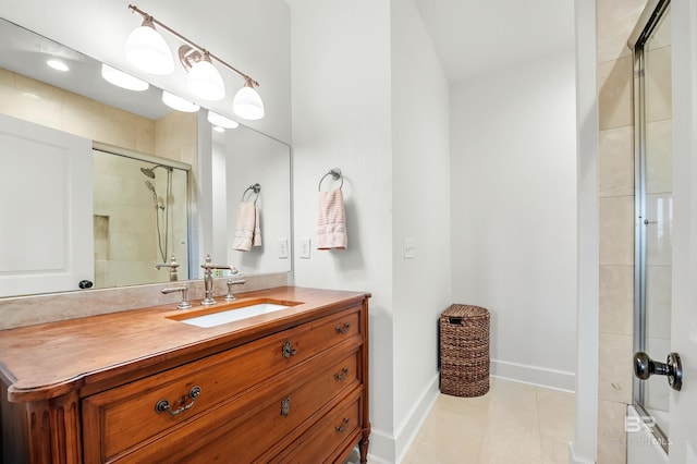 bathroom featuring a tile shower, tile patterned flooring, vanity, and baseboards