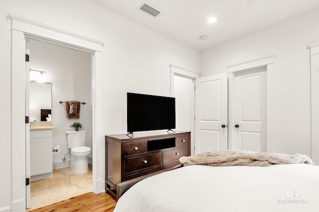 bedroom with light wood-style floors, ensuite bathroom, baseboards, and recessed lighting